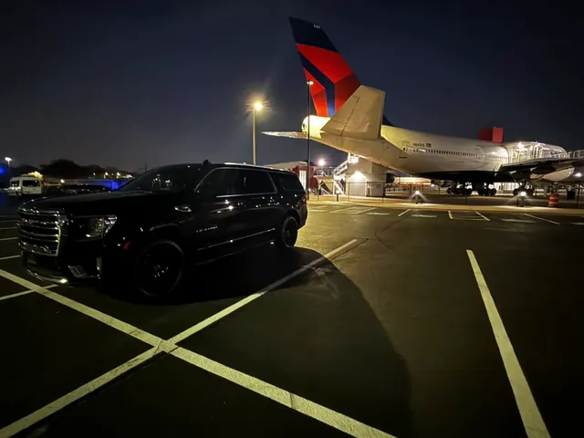 Black GMC Yukon XL at night beside a Delta airliner