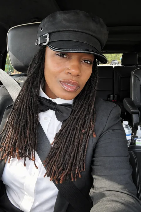 A chauffeur in a cap and bow tie, at the wheel