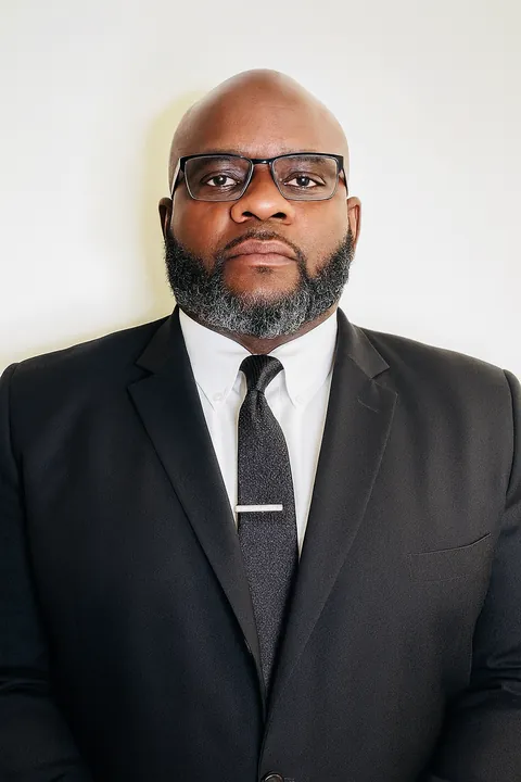 A chauffeur in a black suit and tie