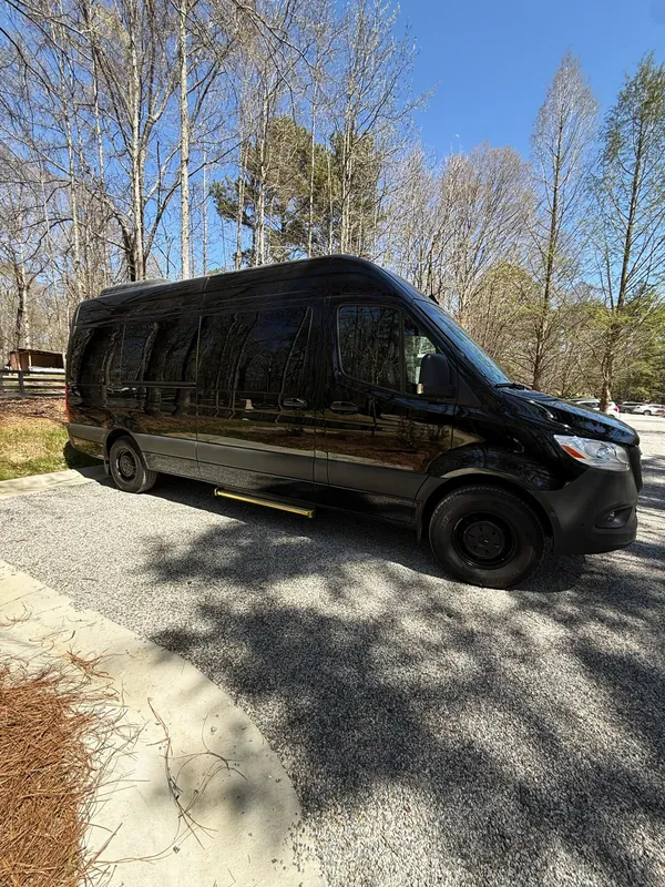 Black Mercedes-Benz Sprinter van on a gravel drive