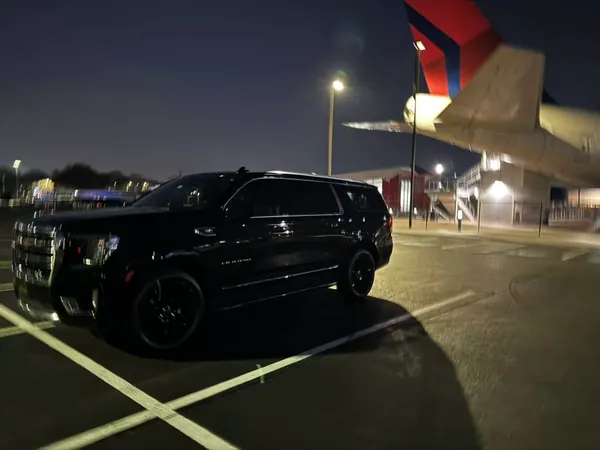 Black GMC Yukon XL and a Delta airliner at night